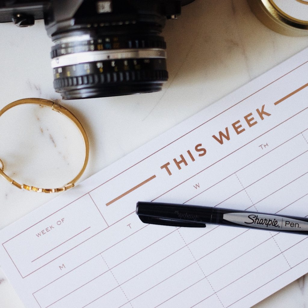 Weekly planner open with camera and writing utensil